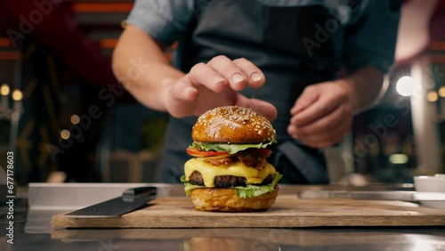 Close-up of a chef pinning a burger with beef patty with vegetables and cheese cooked in the professional kitchen of an Italian restaurant photo