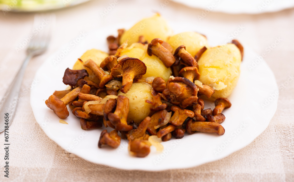 Delicious fried chanterelle mushrooms with new potatoes on a white plate