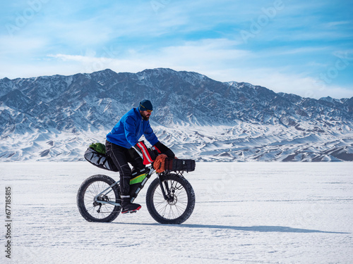 A man travels on a fat bike on the ice of a frozen mountain lake. Traveling in winter. Extreme expedition