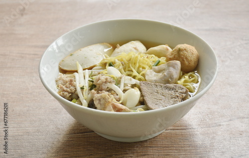 boiled Chinese yellow egg noodles with entrails and fish ball in soup on bowl