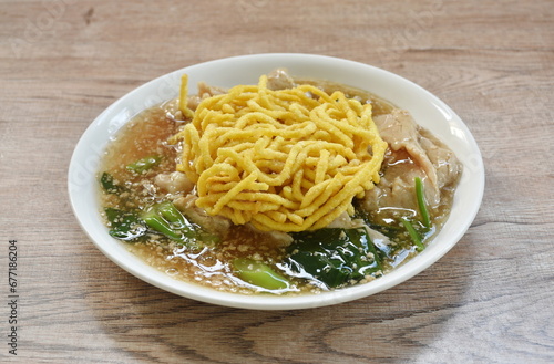 crispy fried egg noodle with slice soft marinated pork and Chinese kale dressing gravy sauce on plate