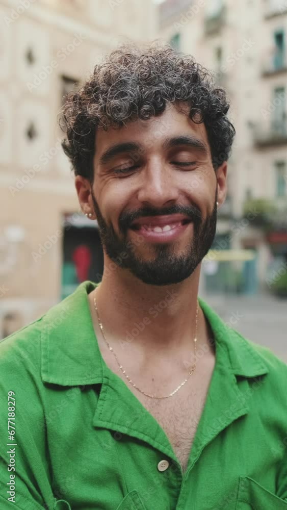 Handsome brunette guy with beard, dressed in green shirt, crosses his arms while looking at camera