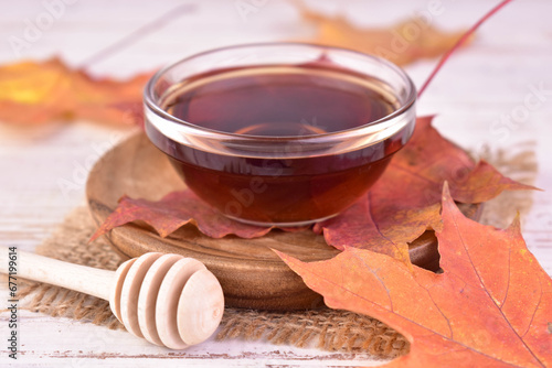 Maple syrup in a bowl on a background of maple leaves.Close-up.
