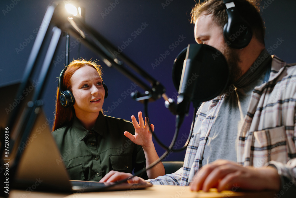 Man having conversation with woman in internet broadcast using professional microphone and audio mixer. Online radio station host recording podcast interviewing guest in late night talk show. Man having conversation with woman in internet broadcast using professional microphone and audio mixer. Online radio station host recording podcast interviewing guest in late night talk show.