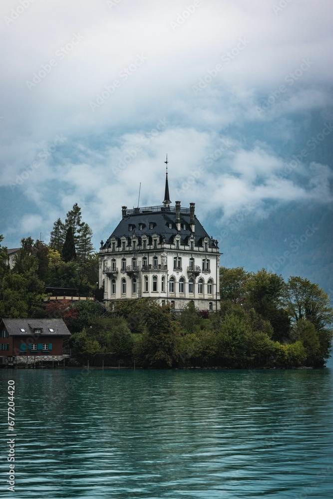 Vertical of the historical castle Seeburg in Switzerland surrounded by the teal lake Brienz