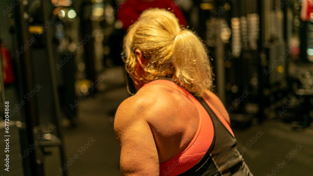 Fit blonde female with toned muscles working out arms at the gym Fit blonde female with toned muscles working out arms at the gym