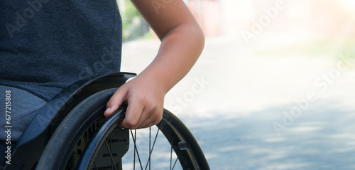 Boy's hand on the wheel of a wheelchair