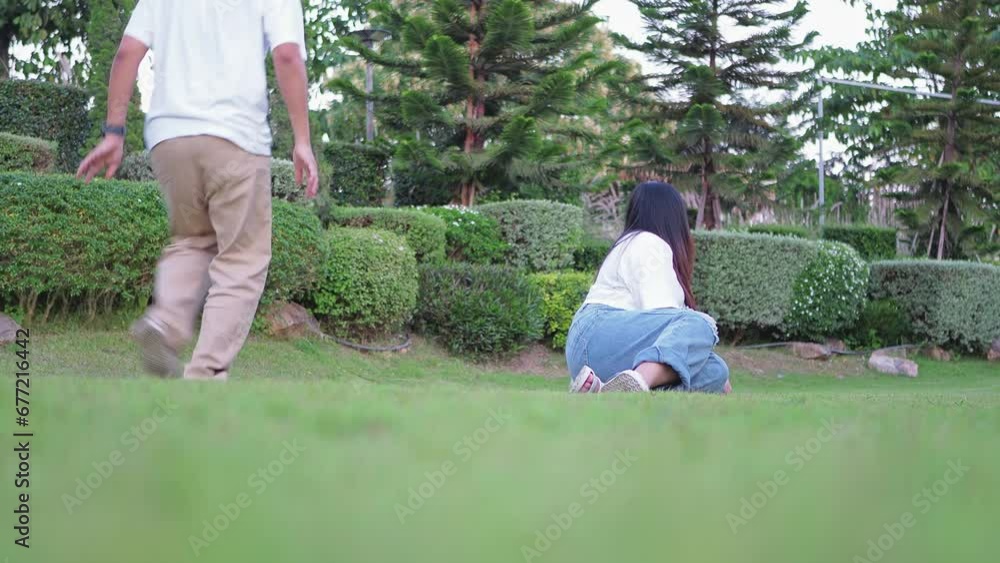 Asian young cheerful couple playing with their fluffy Shih Tzu dog at the park on the summer day. Having a good time with a family. Asian young cheerful couple playing with their fluffy Shih Tzu dog at the park on the summer day. Having a good time with a family.
