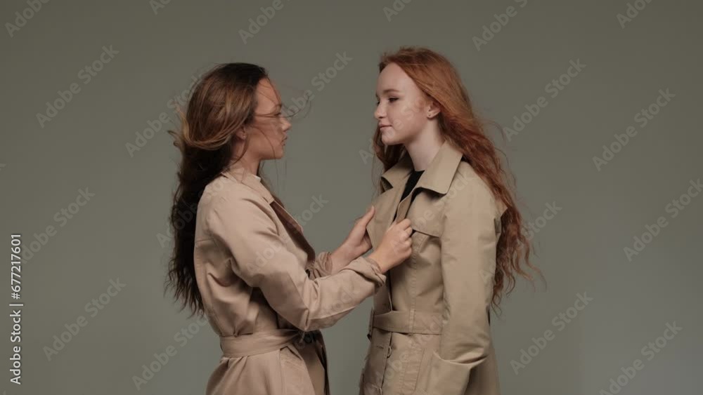 Two stylish models in a trench coat in the studio on a gray background. Two stylish models in a trench coat in the studio on a gray background.