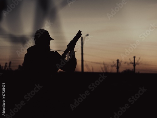 Silhouette of a soldier holding a gun during sunset