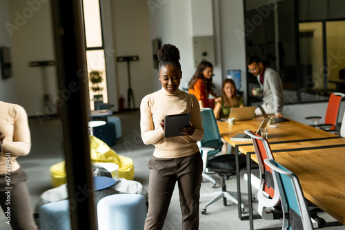 Young African American woman standing with digital tablet in front of her team at the office © BGStock72
