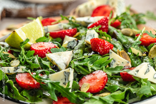 Healthy Green Salad Leaves, Slices of Fresh Strawberries. Concept healthy and balanced eating. Food recipe background. Close up