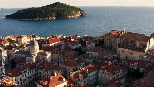 Drone flies over historic old town Dubrovnik Croatia capturing a beautiful aerial shot of rooftops and Adriatic Sea during a summer sun set