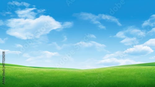 Lush green grass under bright blue sky with clouds 
