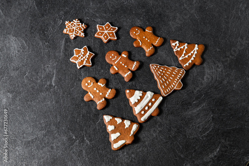 baking, cooking and food concept - close up of iced gingerbread cookies in shape of christmas tree on black table top