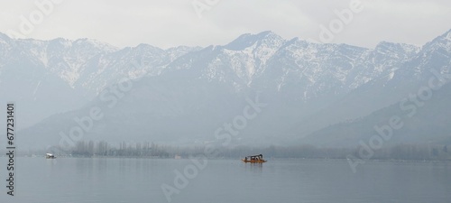Beautiful view of boats on a lake and huge mountains in a background © Wirestock