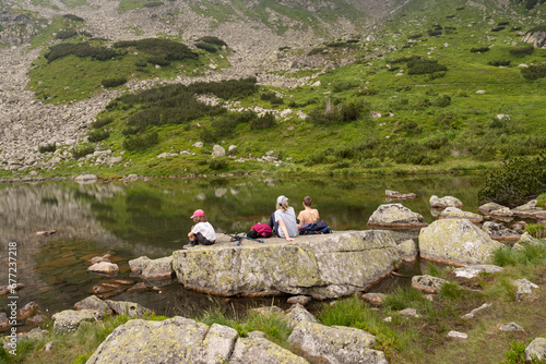 Obraz na płótnie three young tourists resting by a mountain lake w salonie