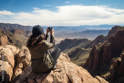 Woman standing on an edge of canyon taking photo