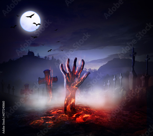 Scary halloween background with spooky undead dead hand and glow fire out of grave on cemetery halloween and full moon lights with bats.