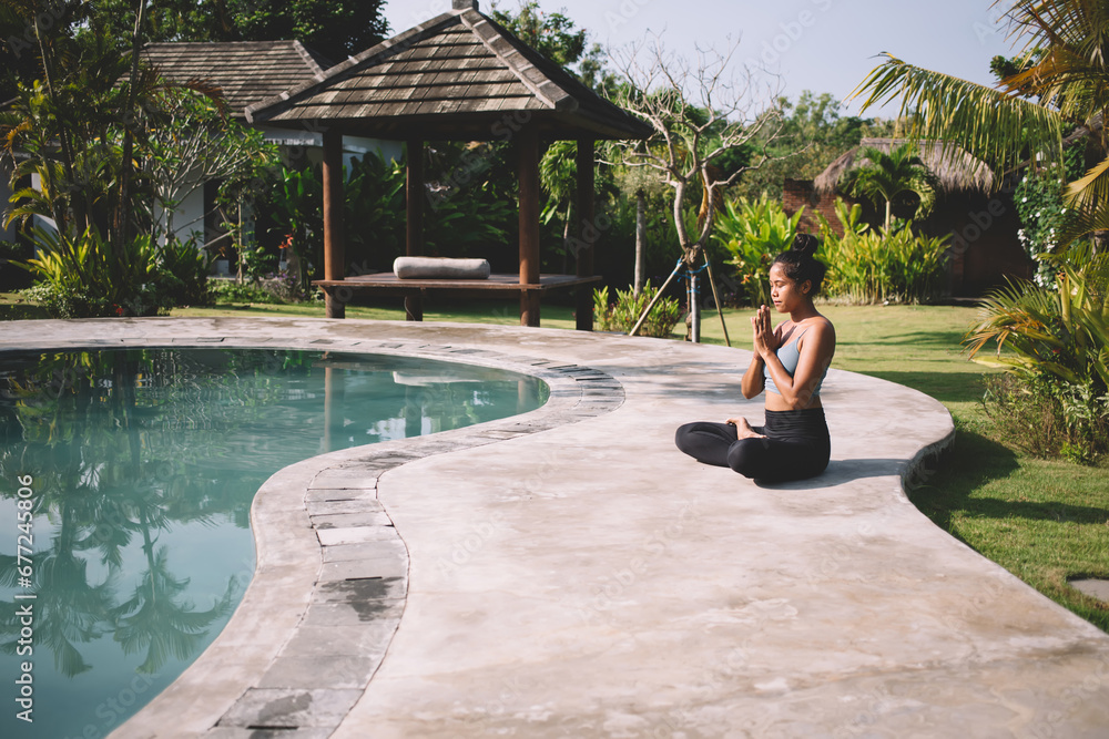 Serene woman meditating on poolside