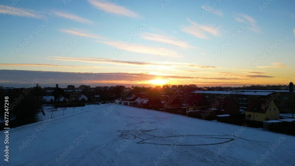 Aerial view of a landscape covered with snow and buildings in the background on a sunny day Aerial view of a landscape covered with snow and buildings in the background on a sunny day