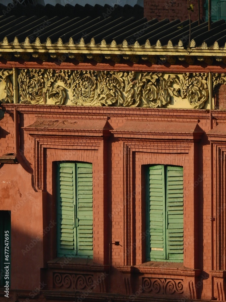 Closeup shot of a red brick building with green window shutters