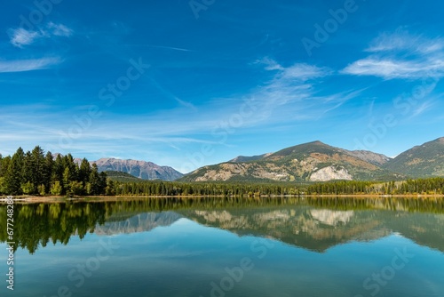 Fototapeta Naklejka Na Ścianę i Meble -  Trees and rocky mountains reflecting on the surface of a tranquil lake