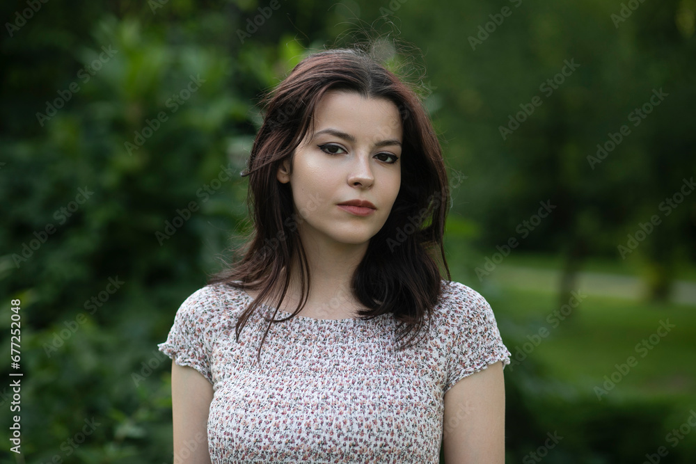 Portrait of a beautiful confidente brunette girl in dress posing in the park, tree background.
Portrait of a beautiful confidente brunette girl in dress posing in the park, tree background.