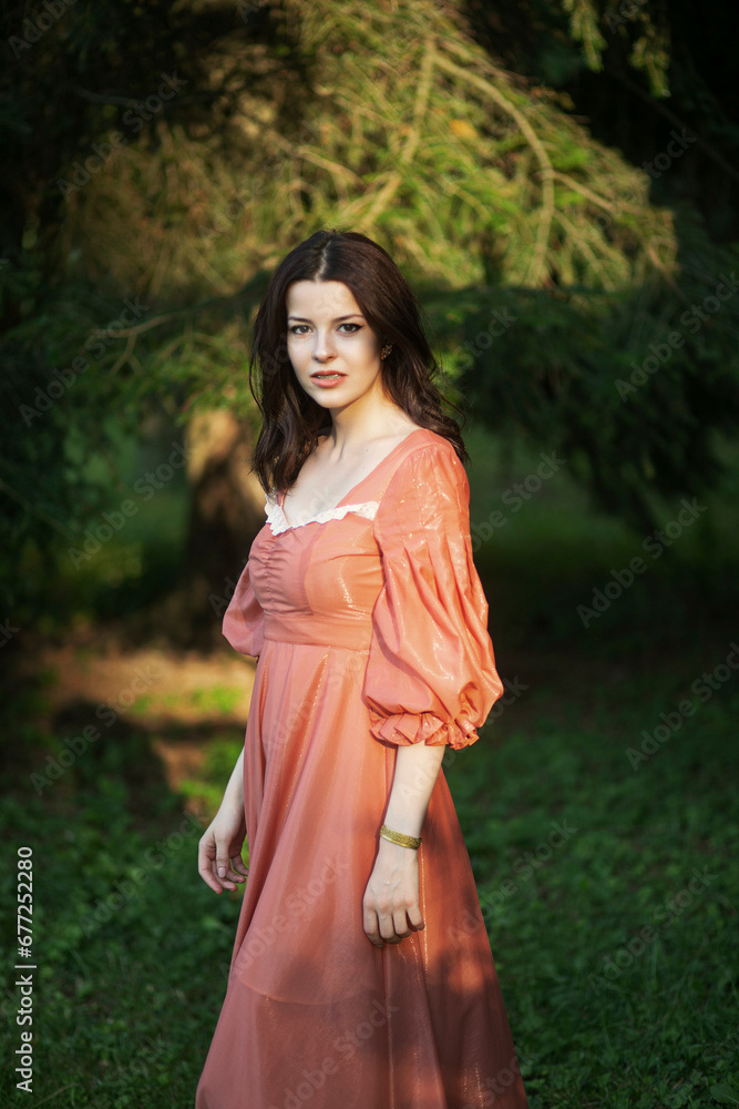 Portrait of a beautiful brunette female model in dress posing in the park, tree background.
Portrait of a beautiful brunette female model in dress posing in the park, tree background.