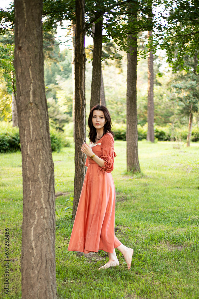 Beautiful brunette girl with makeup in dress posing in the park, tree background.
Beautiful brunette girl with makeup in dress posing in the park, tree background.