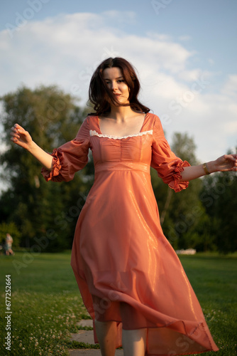Young woman in a vintage dress dance in the park.