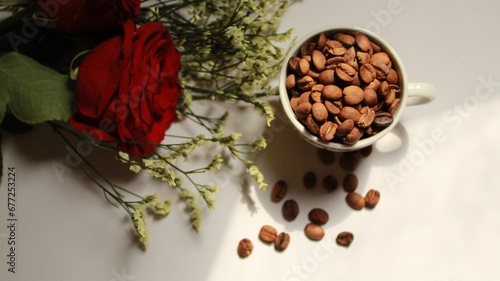 Top view of a cup with coffee beans and the table with a bunch of flowers