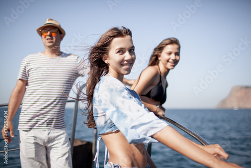 A group of friends are resting on a boat against the background of the sea and island © Вероника Зеленина