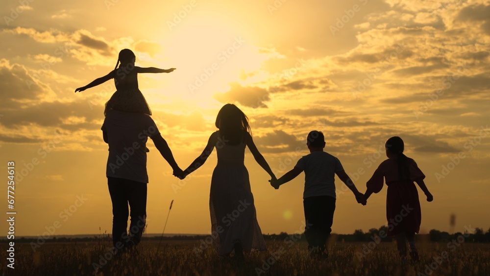 Kid Daughter on shoulders of Dad mom son, walk hand in hand outdoors. Parental care for children. Big family, group of people in nature. Family with children run across grassy in park. Kids team