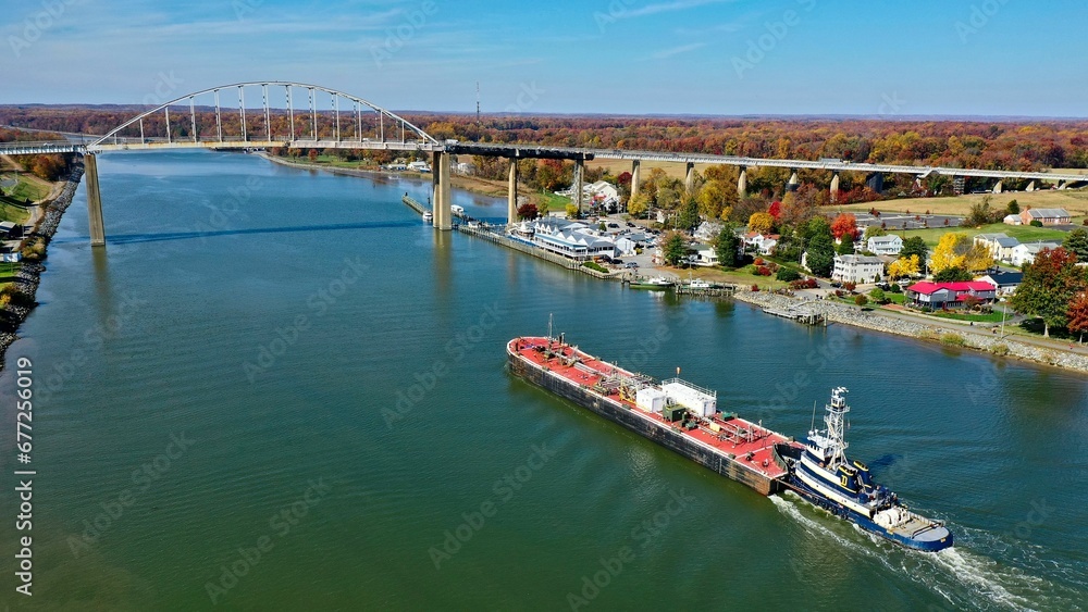Aerial view of a ship in a river with a bridge in the background