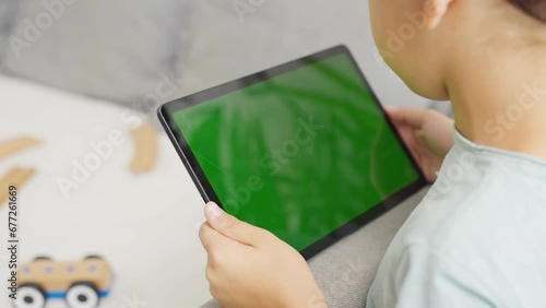 Close up kids hands holding, tapping on a tablet with green screen. Mock up