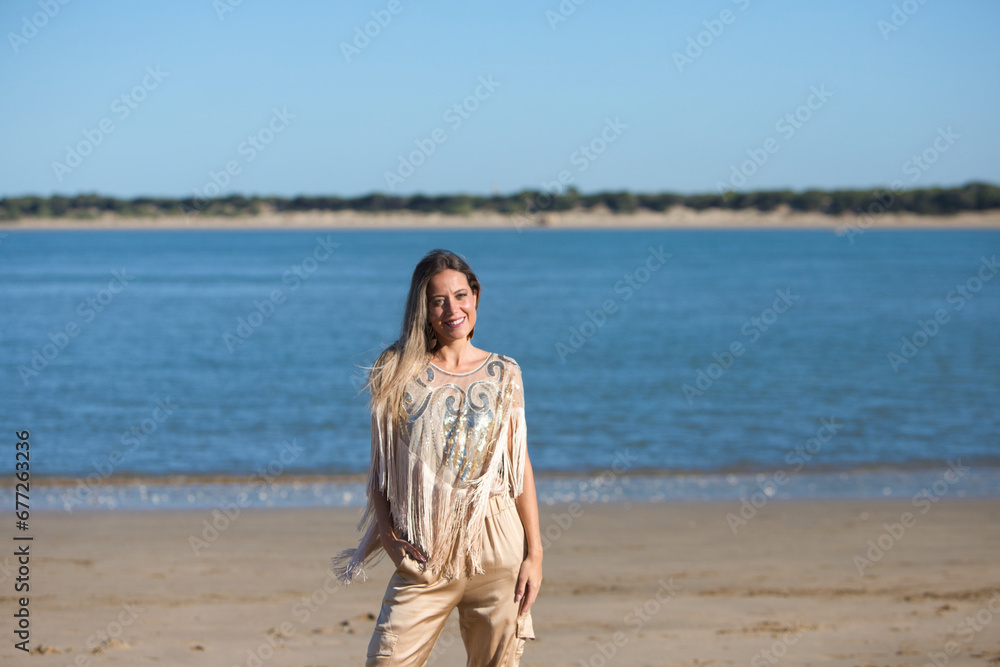 Beautiful young blonde woman walks along the shore of the beach on the south coast of Spain. The woman is happy and smiling and enjoys the sunny day. Travel and holiday concept. Beautiful young blonde woman walks along the shore of the beach on the south coast of Spain. The woman is happy and smiling and enjoys the sunny day. Travel and holiday concept.