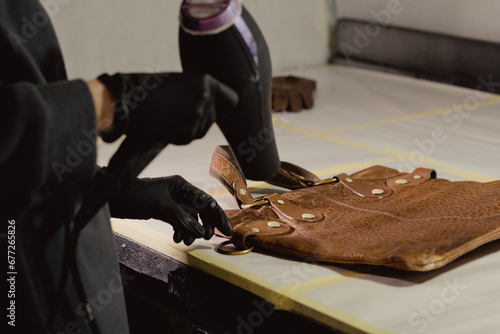 The workplace of the master restorer. Repair of leather goods. Blow-drying of the repair part on a leather bag. A hair dryer in women's hands