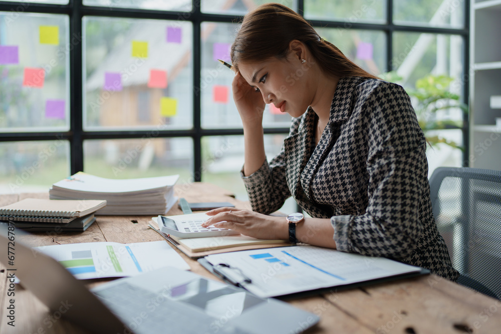 female employee holds a pen and checks investment financial documents. female employee holds a pen and checks investment financial documents.