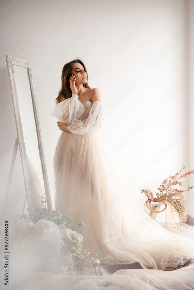 Tender bride in a wedding dress colour of champagne looks out the window