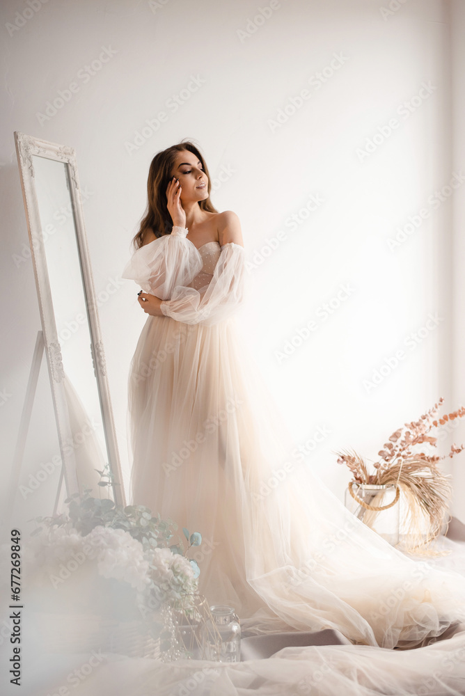 Tender bride in a wedding dress colour of champagne looks out the window Tender bride in a wedding dress colour of champagne looks out the window