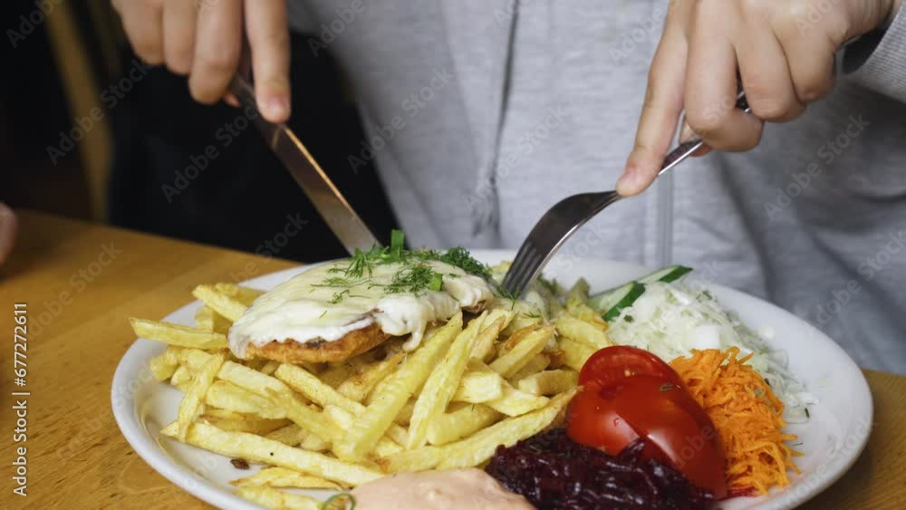 A girl in a cafe eats French fries, chop and vegetables. Close-up. A girl in a cafe eats French fries, chop and vegetables. Close-up.