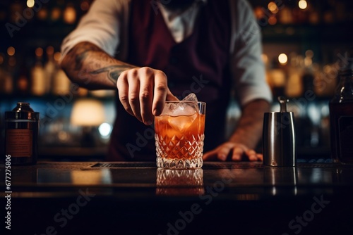 barman gently pours finished cocktail from glass shaker into glass. Body of bartender in black apron on background.