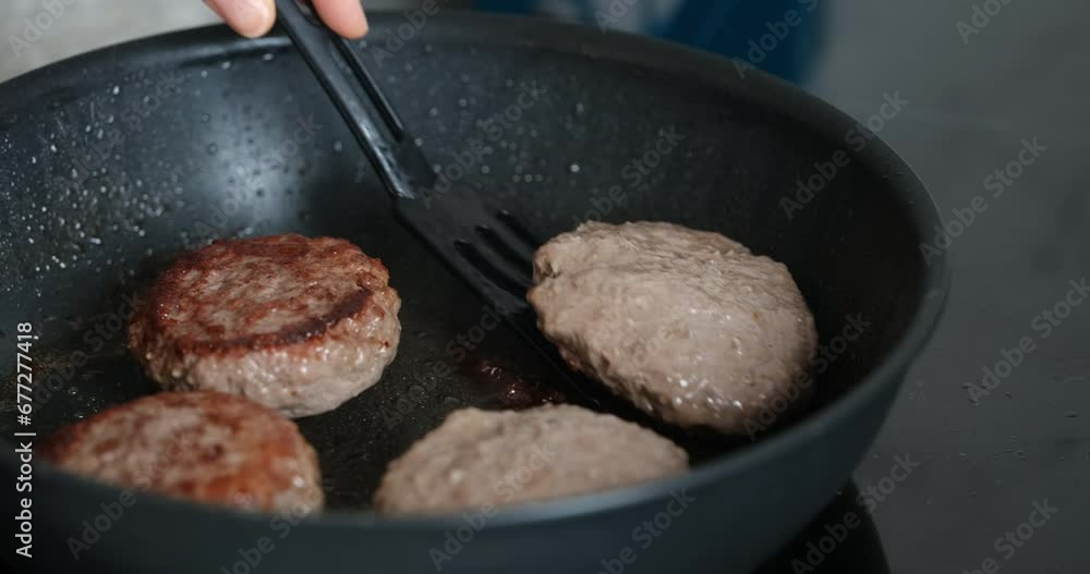 A person flipping over beef patties on a pan. Close up. A person flipping over beef patties on a pan. Close up.