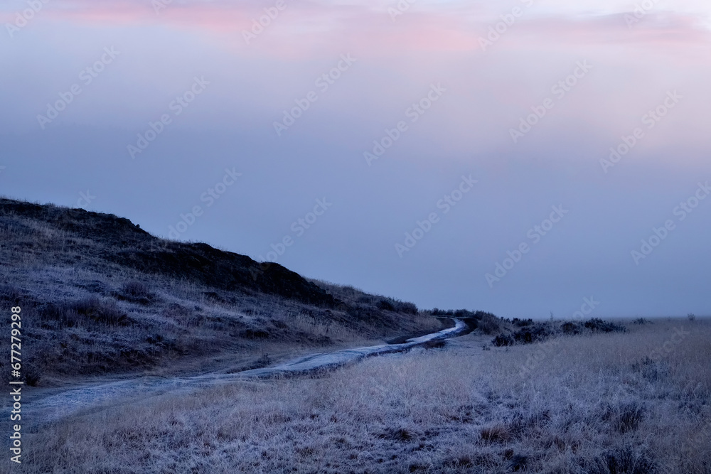 Purple morning dawn view of a mountain bike trail in the Alps. Winding gravel dirt road.