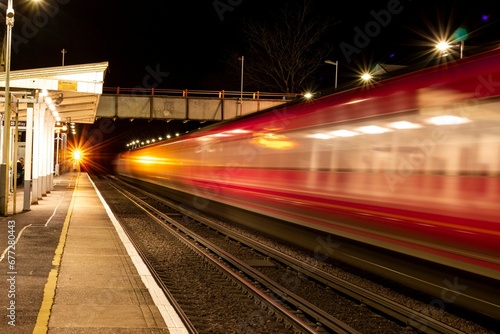 Beautiful shot of a fast moving red train at night at a station in London