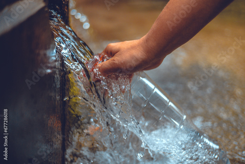 Pure water from the spring is collected in a glass bottle. Transparent cold water from a natural spring pours into a bottle in the autumn forest. Water source concept. photo