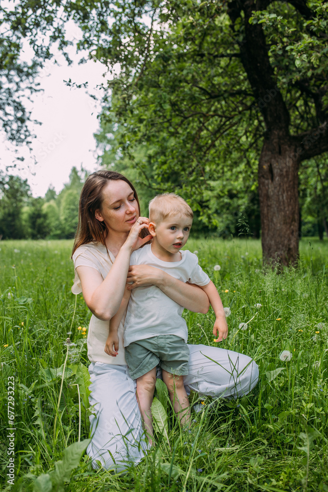 Fototapeta premium Young woman mom and son play in nature, spend time together and have fun