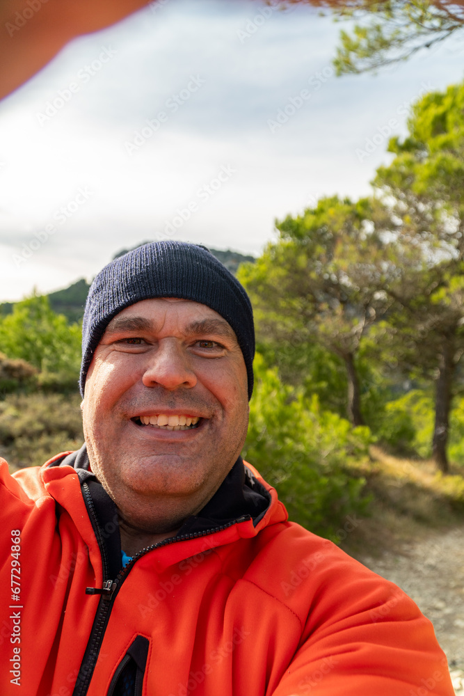 Smiling man takes a selfie in the forest on a cold winter sunset Smiling man takes a selfie in the forest on a cold winter sunset