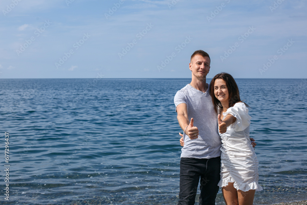 Happy couple against the background of the sea shows class, horizontal frame